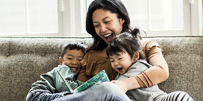 Don't Miss the Opportunity for a Spousal IRA - A woman holds each of her children under her arms while they are all laughing on the couch together