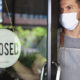 New COVID Relief Law passed in 2020. A man in a mask stands inside his shop, turning the open sign to closed.