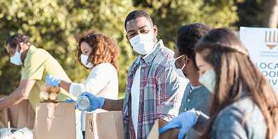 Charitable Contributions Deduction Liberalized For 2021 - A group of masked volunteers help load groceries for charity