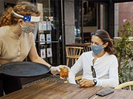 Congress Has Authorized a Second Round of PPP Loans, A server wearing a mask passes a drink to a customer on a restaurant patio.