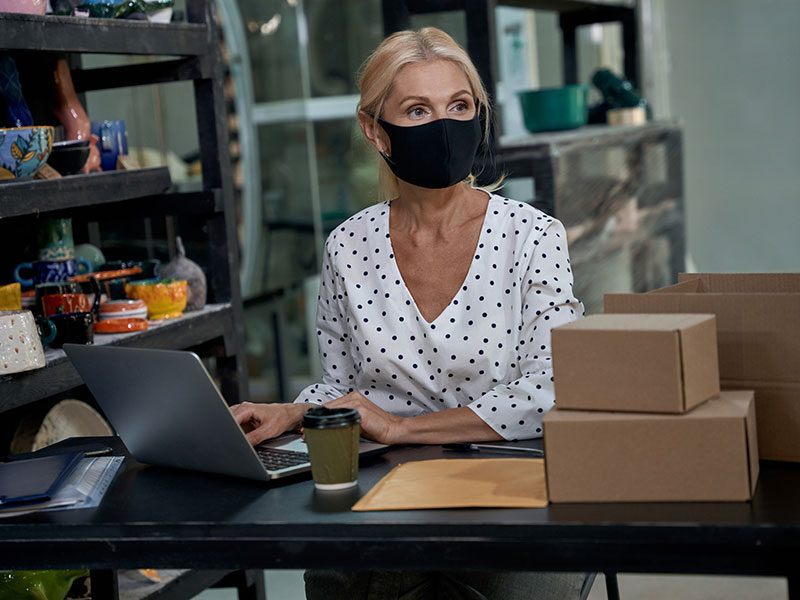 types of business a woman in a mask works in her garage on her laptop