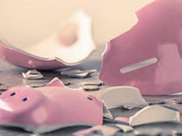 Unemployment Fraudsters May Create A Tax Nightmare for Unsuspecting Taxpayers, A broken piggy bank lies smashed on a table with a few coins scattered about.