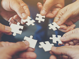 What Is A Joint Venture? Four hands come together holding puzzle pieces
