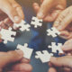 What Is A Joint Venture? Four hands come together holding puzzle pieces