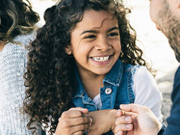 Are You Missing Out On The Increased Child Tax Credit? A young girl with curly black hair smiles at an adult.