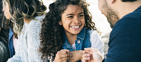 Are You Missing Out On The Increased Child Tax Credit? A young girl with curly black hair smiles at an adult.