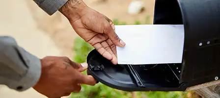 Have You Received The IRS Reminder Letter? A hand reaches into a black old fashioned, metal mailbox.