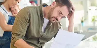 Haven't Filed Tax Returns. A stressed out man holding his head in his hands looks at papers in his hand.