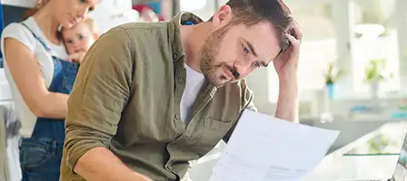 Haven't Filed Tax Returns. A stressed out man holding his head in his hands looks at papers in his hand.