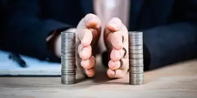 Two hands represent Separating Personal And Business finances by placing them between two separate stacks of coins. effectively dividing them.