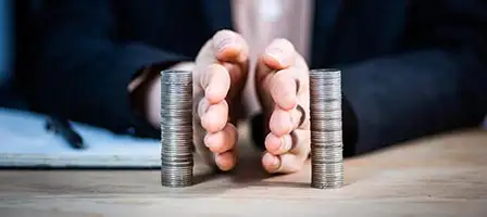 Two hands represent Separating Personal And Business finances by placing them between two separate stacks of coins. effectively dividing them.