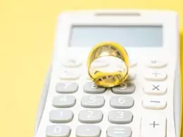 Video Tips: Love & Taxes: Essential Tips For Tax Planning Before You Get Married. A gold wedding ring sits on top of a calculator.