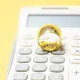 Video Tips: Love & Taxes: Essential Tips For Tax Planning Before You Get Married. A gold wedding ring sits on top of a calculator.