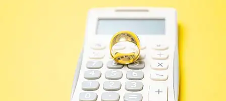 Video Tips: Love & Taxes: Essential Tips For Tax Planning Before You Get Married. A gold wedding ring sits on top of a calculator.