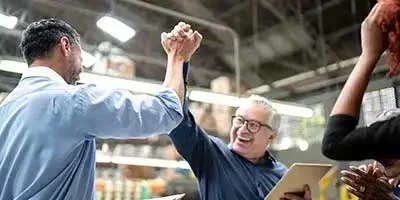 Maximize Your Tax Savings: An Owner’s Guide to Small Business Tax Deductions Two business men high five in an office space