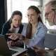Retirement Taxes: No surprises: What Boomers Need to Know Before It’s Too Late. Two seniors and a younger woman look at a laptop in discussions.