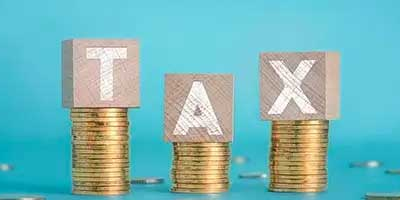 Stacks of coins with blocks spelling "TAX" on a blue background - representing the 2025 Tax Changes