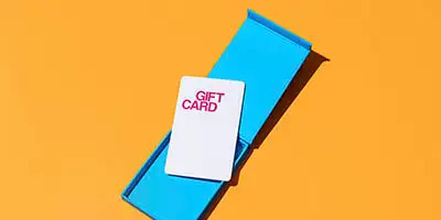 A white gift card with pink text sits atop an open blue box representing Employee Holiday gifts.