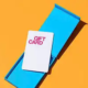 A white gift card with pink text sits atop an open blue box representing Employee Holiday gifts.