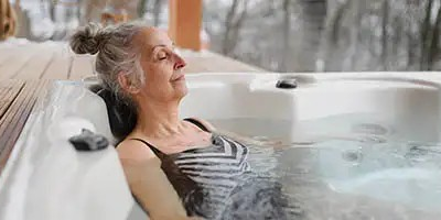 A woman enjoys a relaxing soak in a hot tub, a common project considered for the Medical Home Improvement Tax Deduction.